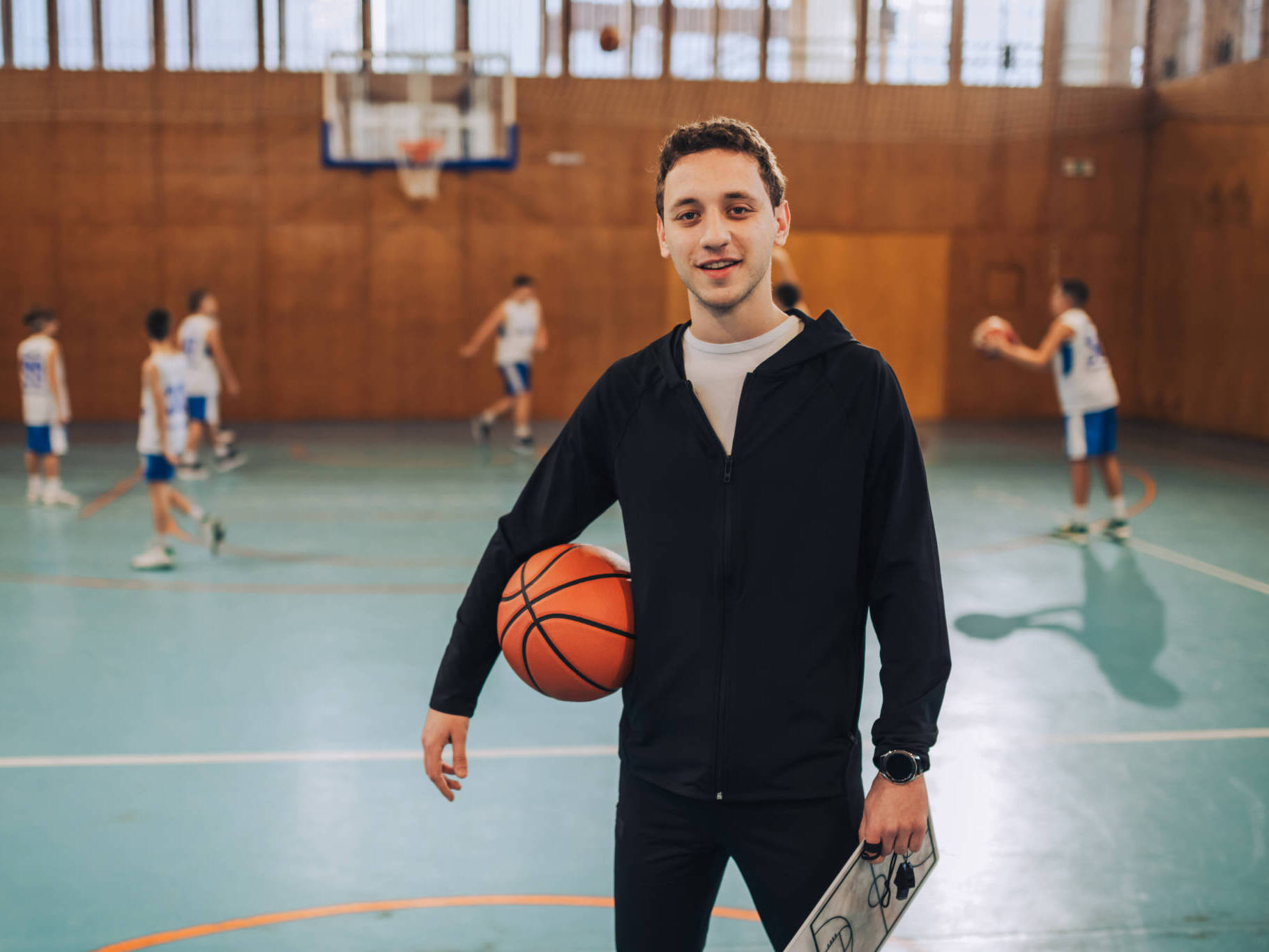 Portrait Of A Basketball Coach Standing With Ball And Clipboard On Court. Portrait Of A Basketball Coach Standing With Ball And Clipboard On Court.